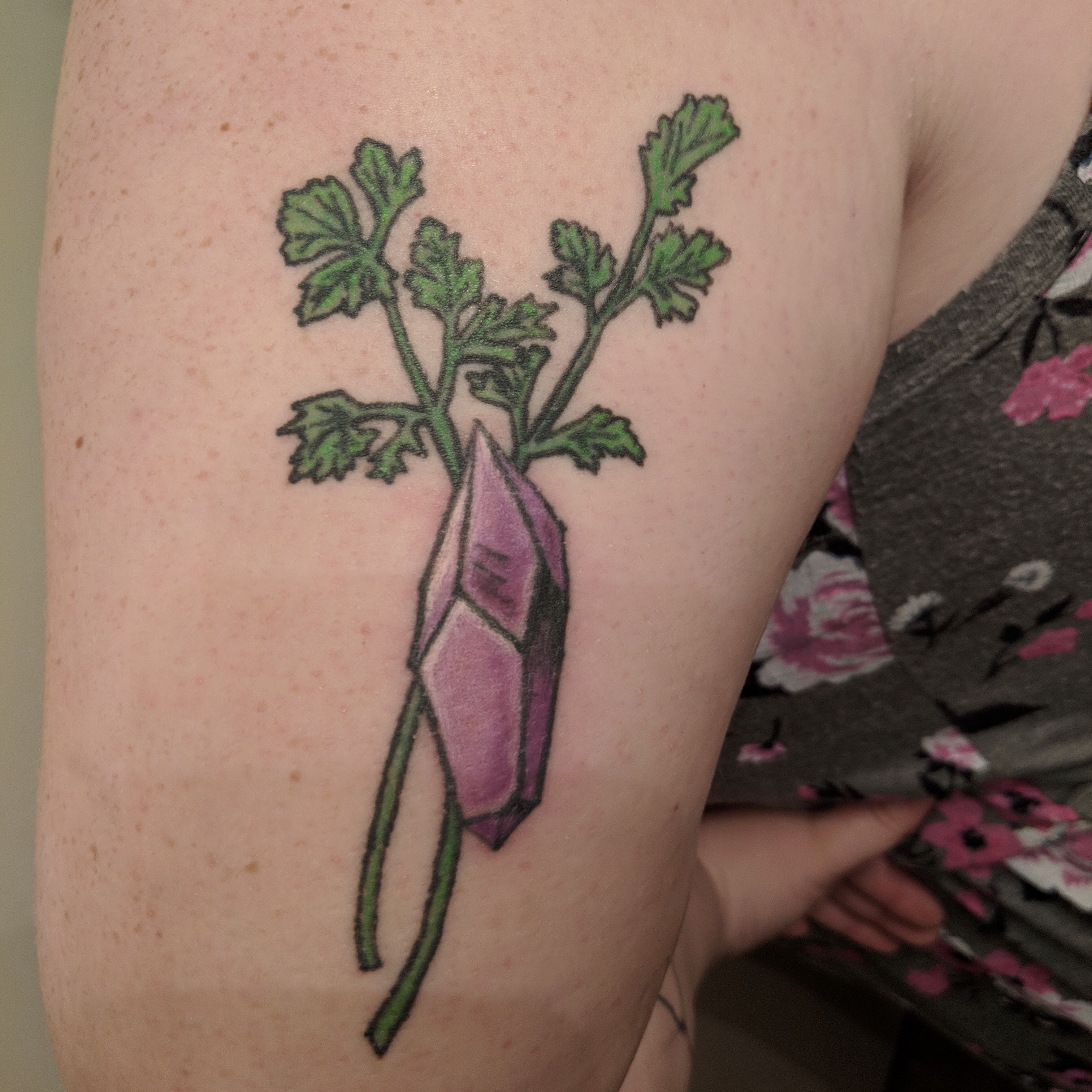 Image of a color tattoo of a purple gem and cilantro on the back of an arm