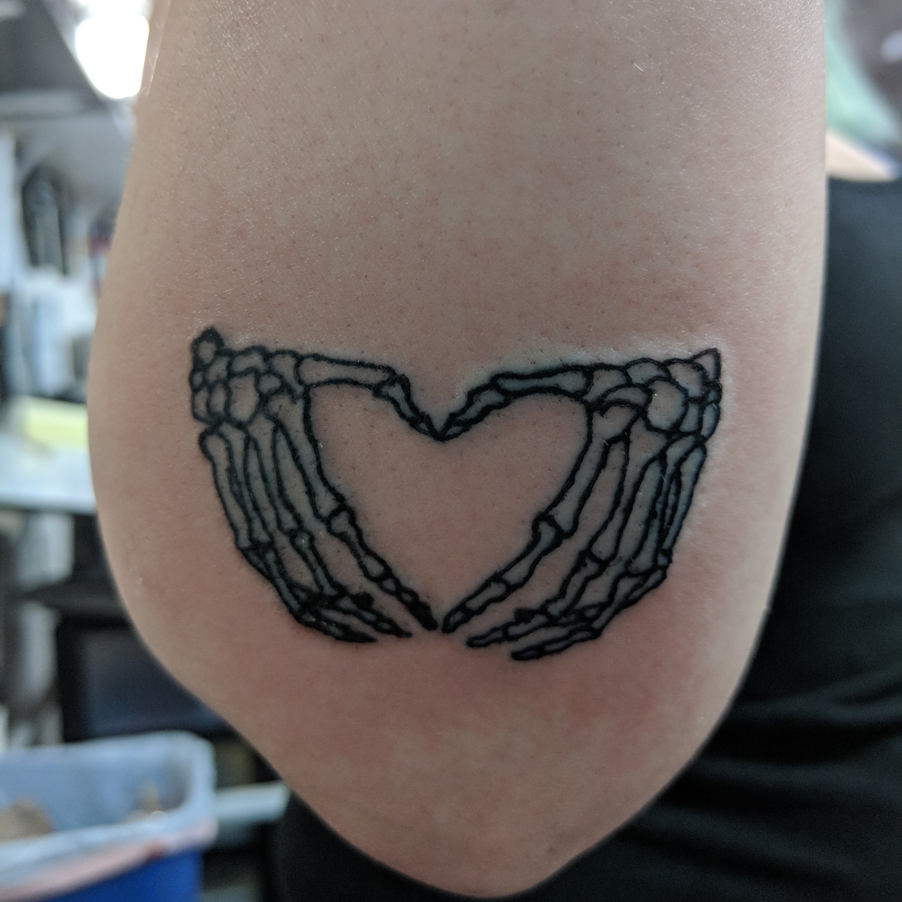 Image of a linework tattoo of skeleton hands making a heart shape