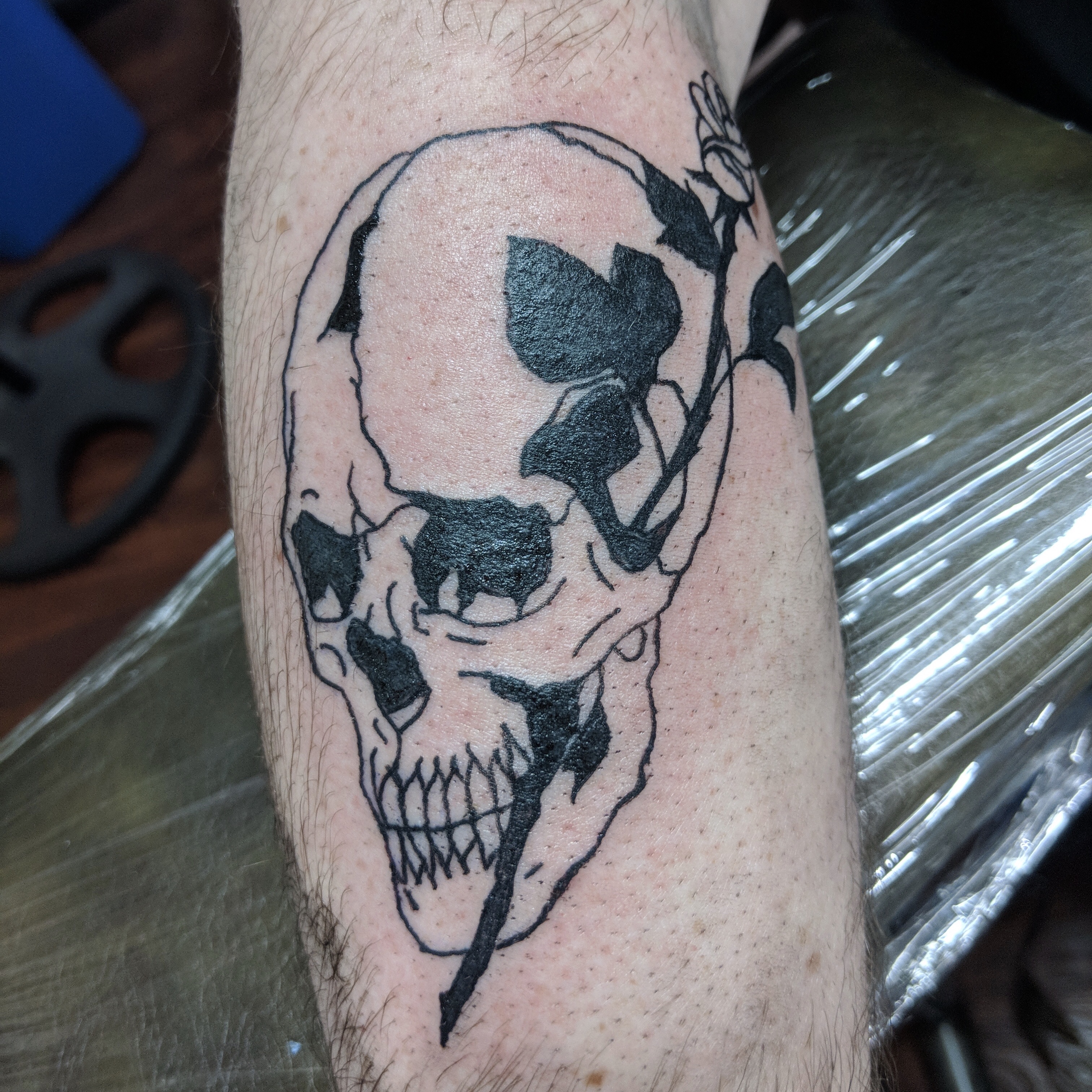 Image of a bold black skull and rose tattoo