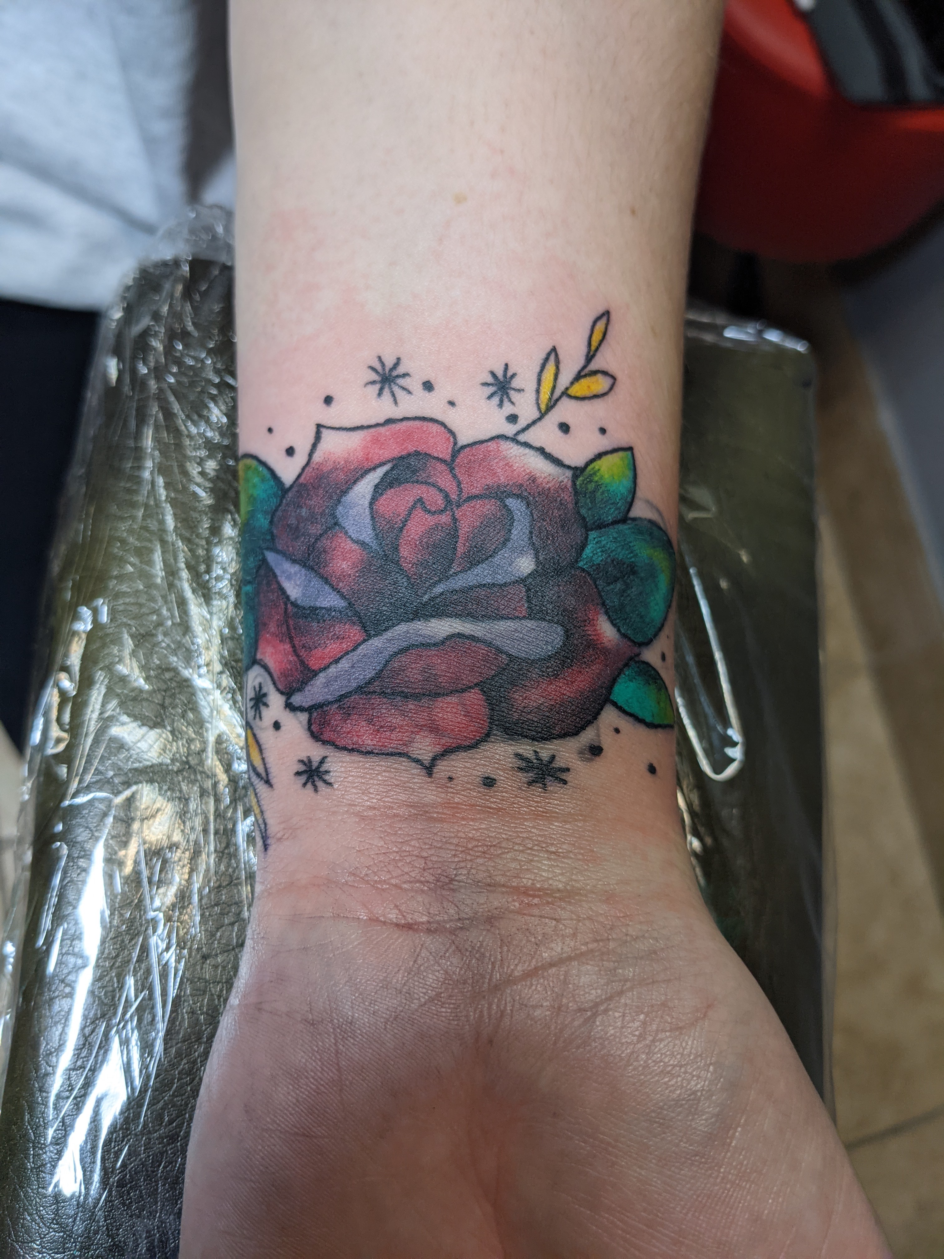 A picture of a rose tattoo in color on an inner wrist