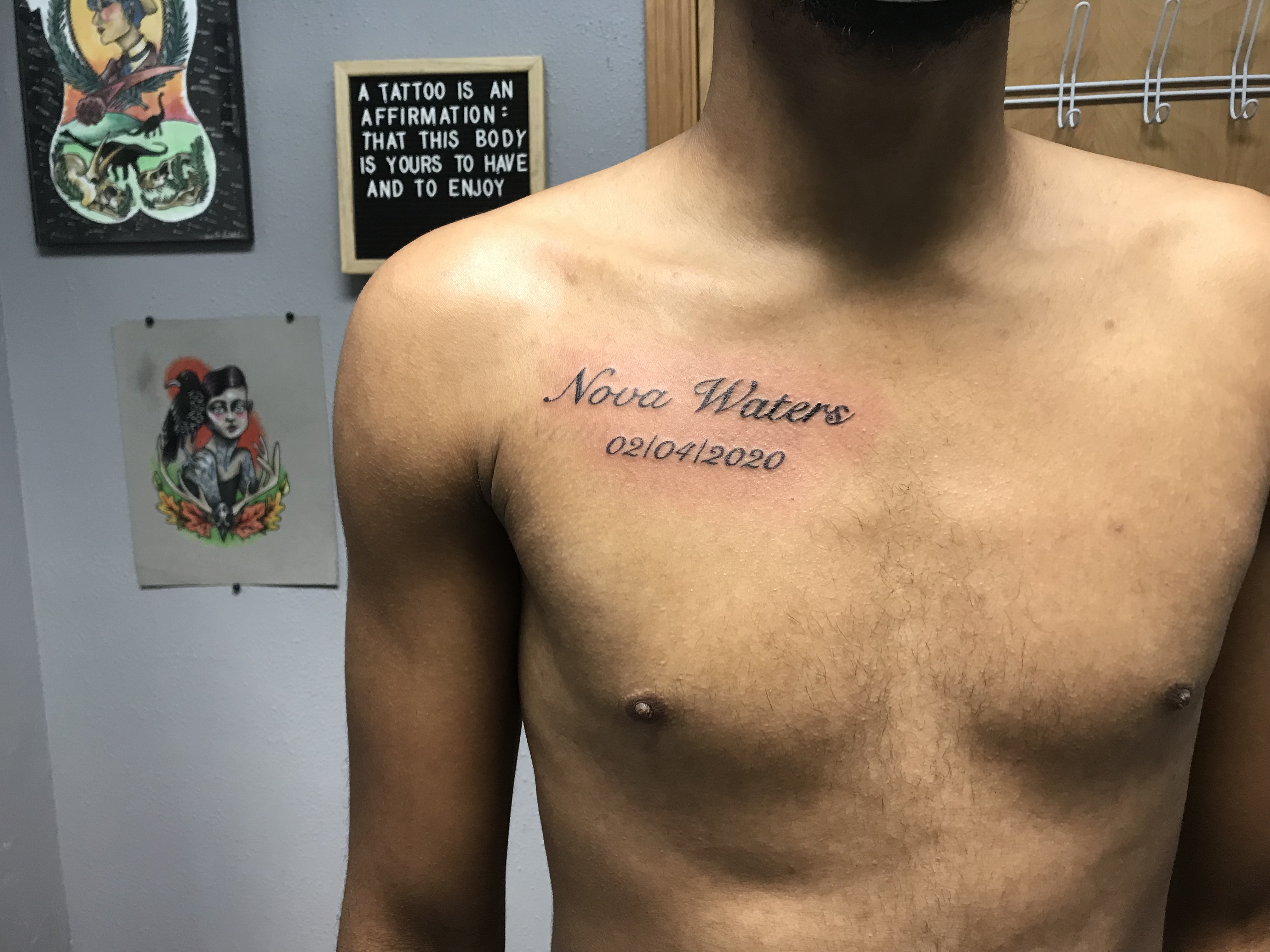 Image of a lettering tattoo on a chest with a quote in the background that says a tattoo is an affirmation that this body is yours to have and to enjoy